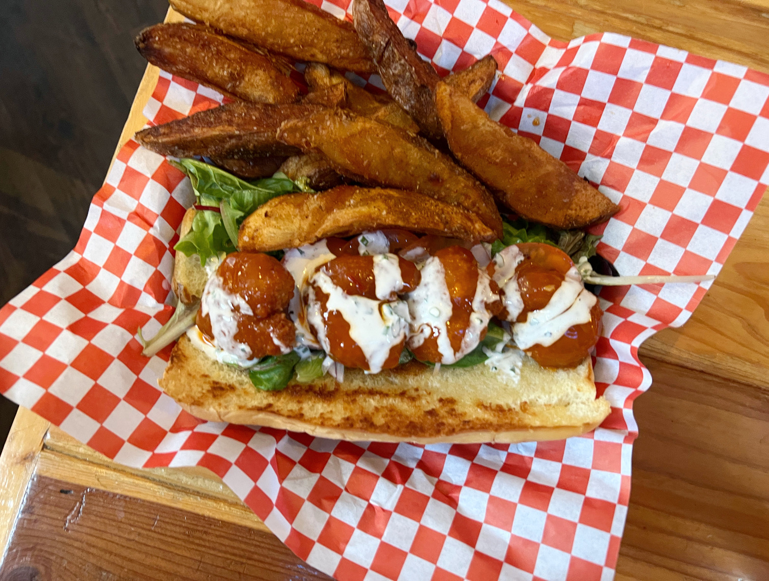 An overhead photo of Watson's firecracker shrimp po boy in a basket lined with a red and white checkered paper. Photo by Alyssa Buckley.