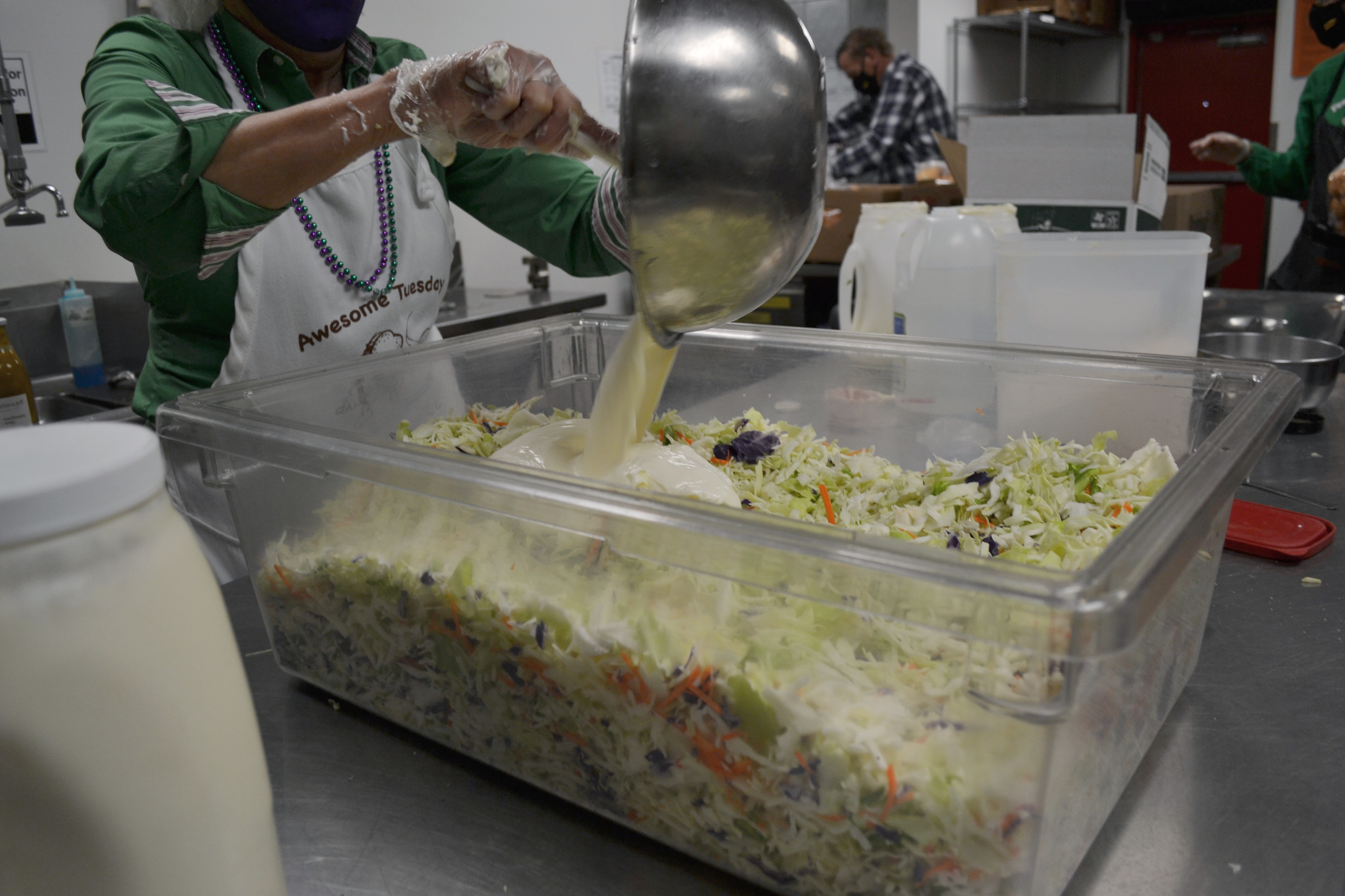 A volunteer pours coleslaw sauce on top of shredded cabbage. Photo by Alyssa Buckley.