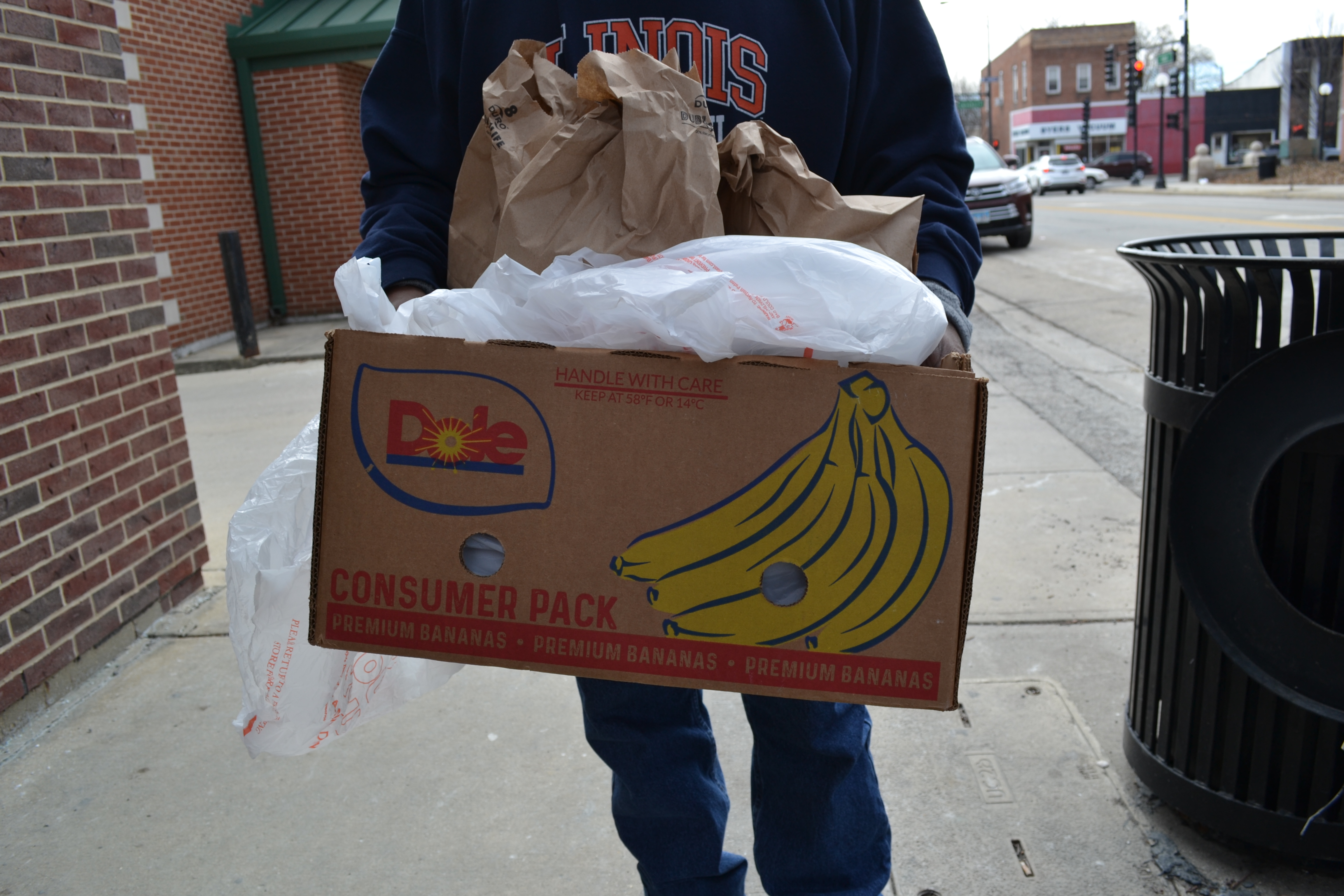 One guest of the Daily Bread Soup Kitchen holds his box of food. The box is a re-used banana box now holding hot lunches and sack lunches to go. Photo by Alyssa Buckley.