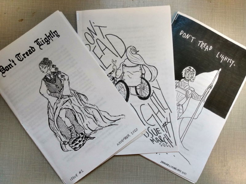 Three issues of the zine Don't Tread Lightly produced by UIUC students Emily Guske and Joey Kreiling. They are black-and-white stapled booklets with covers featuring a stylized title and a cartoon, such as a woman in metal armor holding a flag and a woman lifting her large skirt to step on a coiled snake. The issues shown are Number 2 from November 2020, Number 3 from January/February 2021, and Number 4 from March 2021. Photo by Michael O'Boyle.
