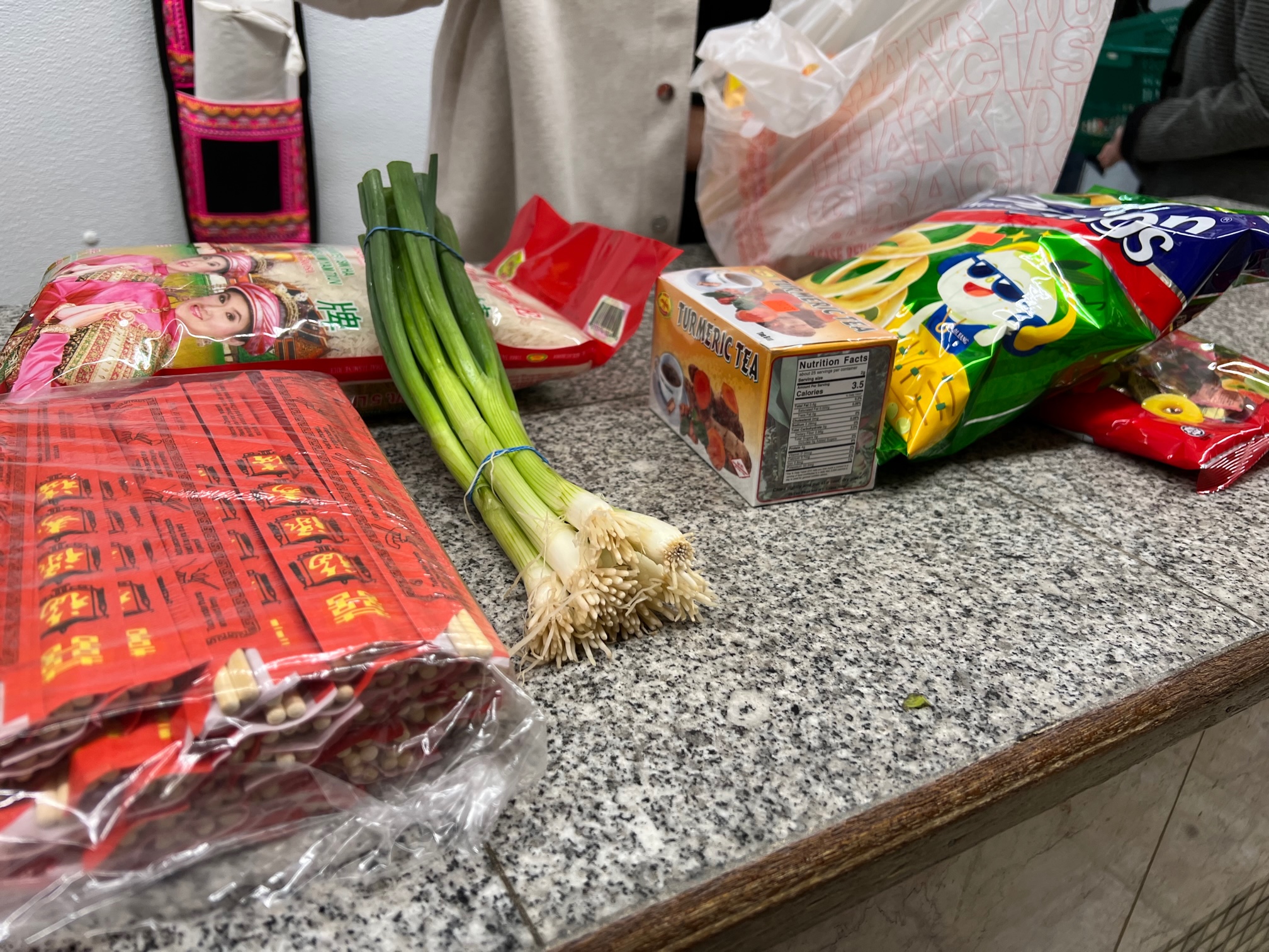 On a gray speckled counter, there is the author's purchase: chopsticks, green onions, snacks, and canned jars. Photo by Alyssa Buckley.