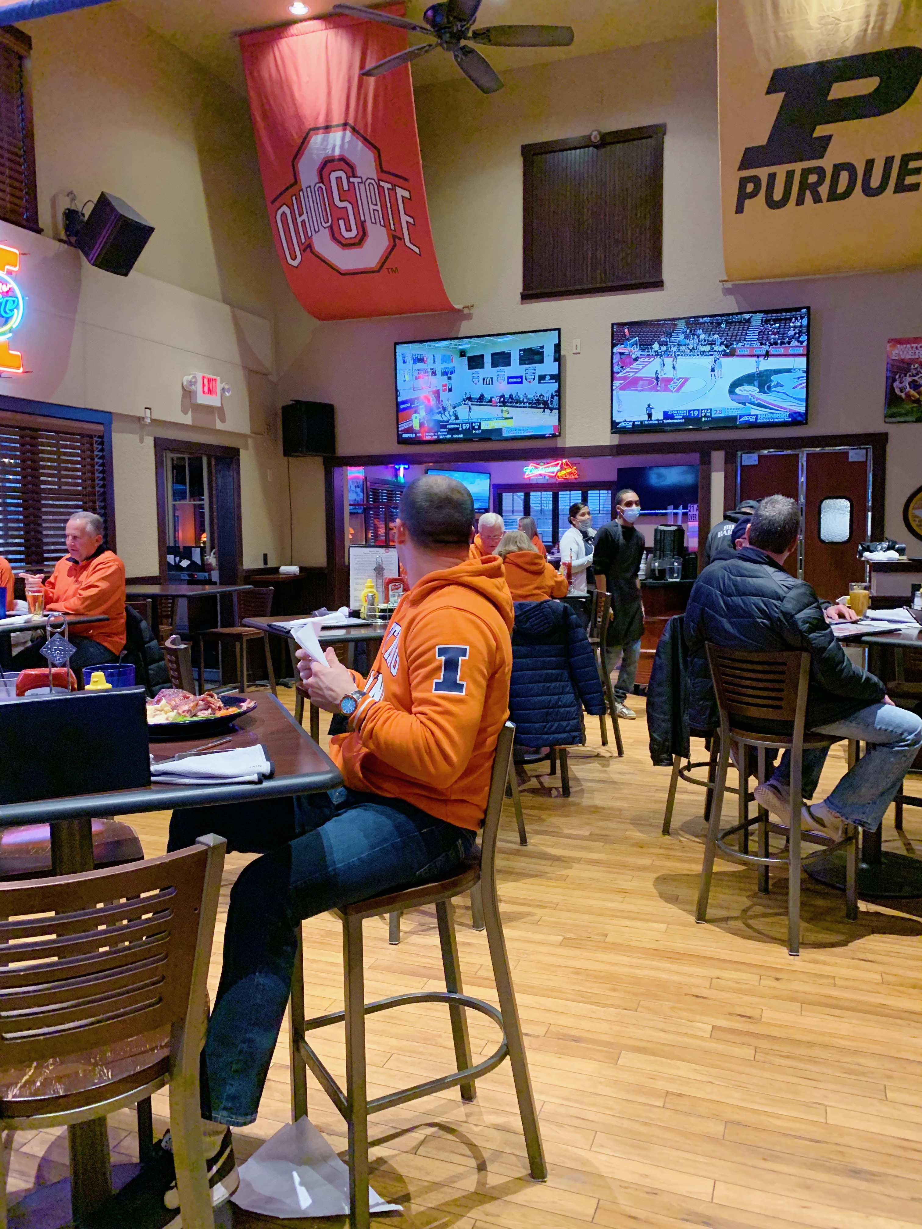 Inside Billy Barooz, there are tall tables with diners enjoying dinner. The tvs are on and playing sports. Photo by Anya Uppal.