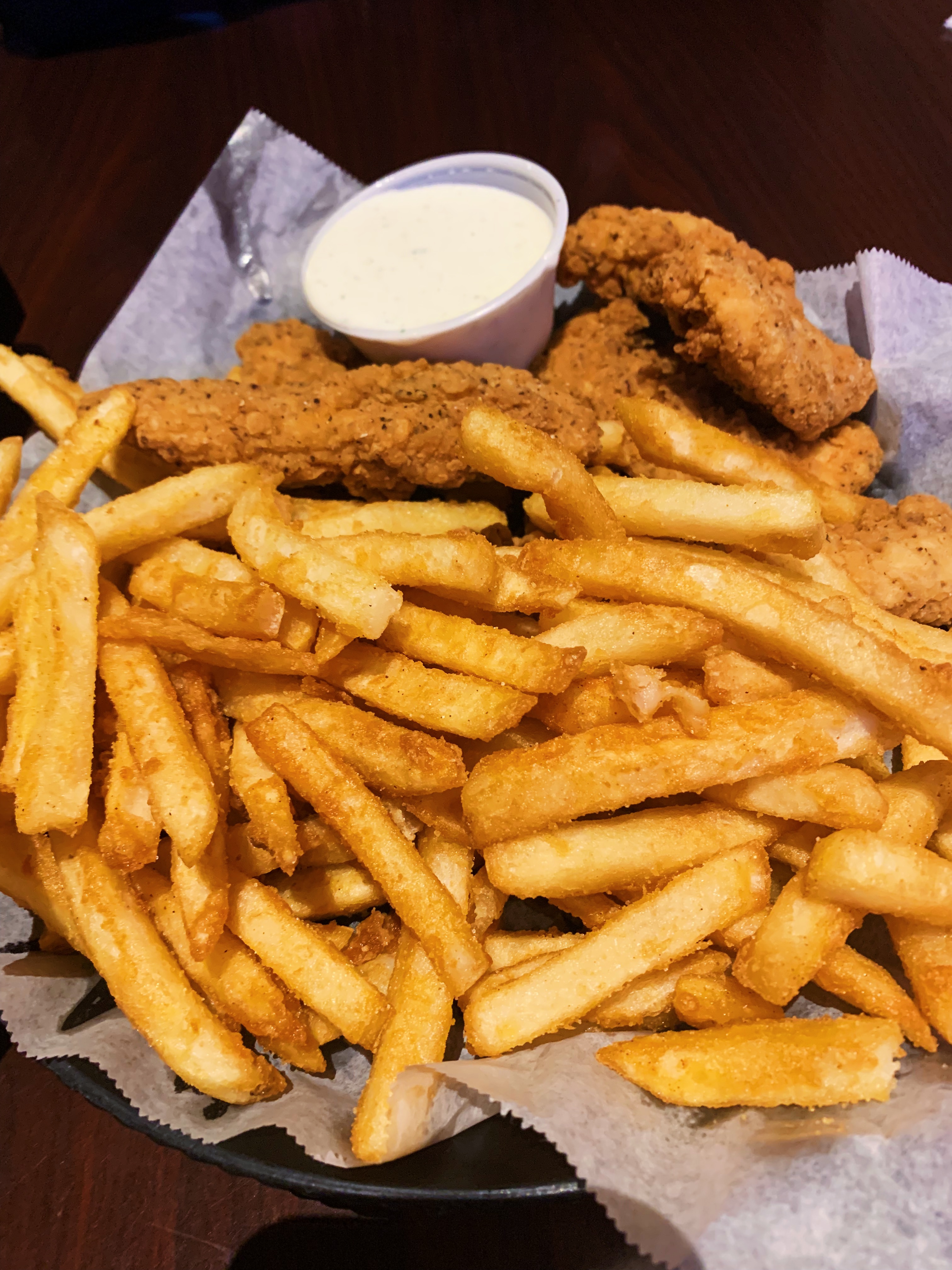 On a black plate, there are lots of fries and three chicken strips. Photo by Anya Uppal.