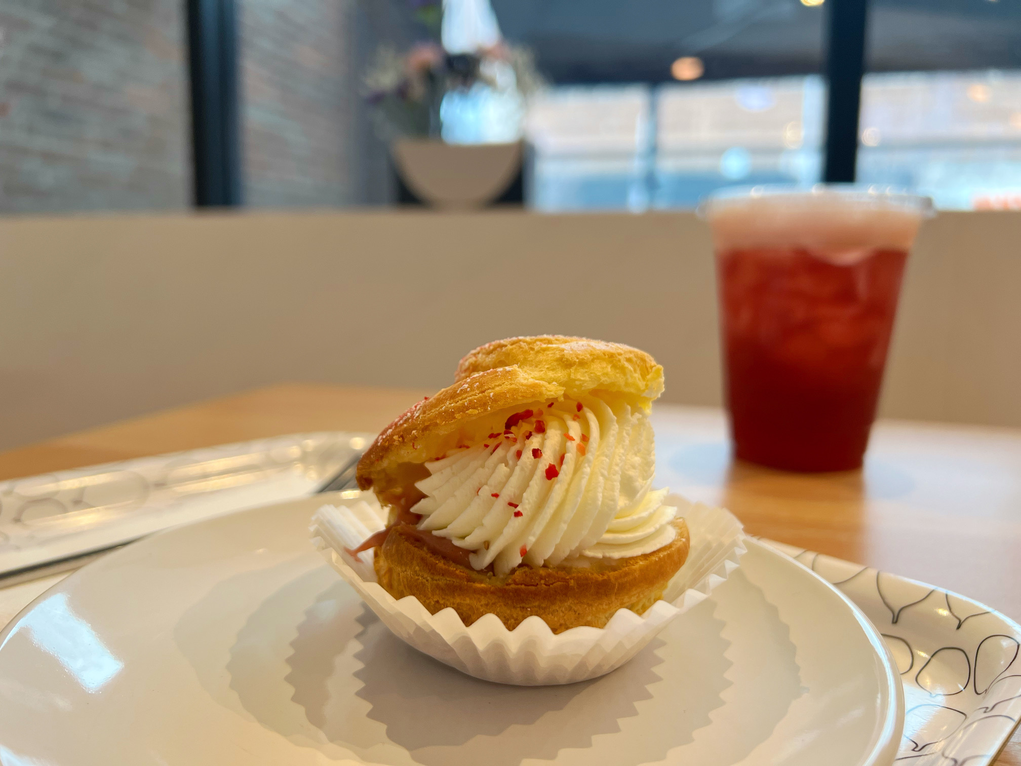 On a white plate on a graphic gray tray, there is a strawberry shu cream sweet from Suzu's: a Japanese Bakery. Photo by Alyssa Buckley.