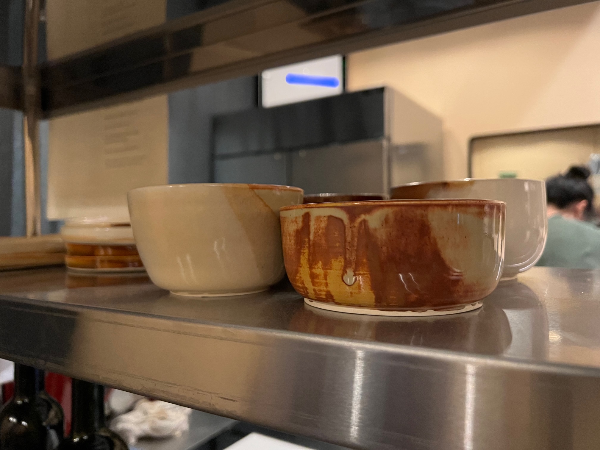 On a silver shelf, there are handmade pottery with brown elements. Photo by Alyssa Buckley.