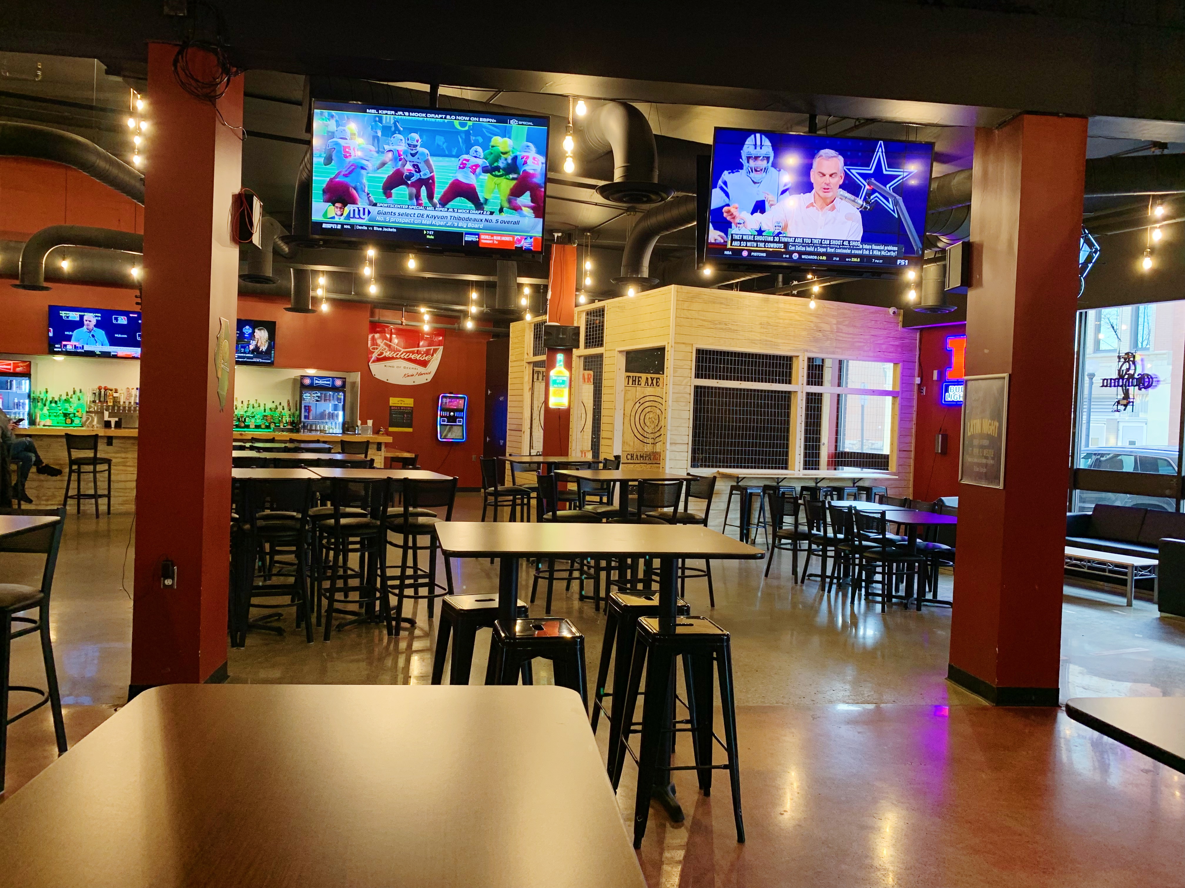 Inside Axe Bar in Champaign, there are wooden bar tables with black backless barsools in a large open area. There are no partons pictured in the dining area. Photo by Anya Uppal.