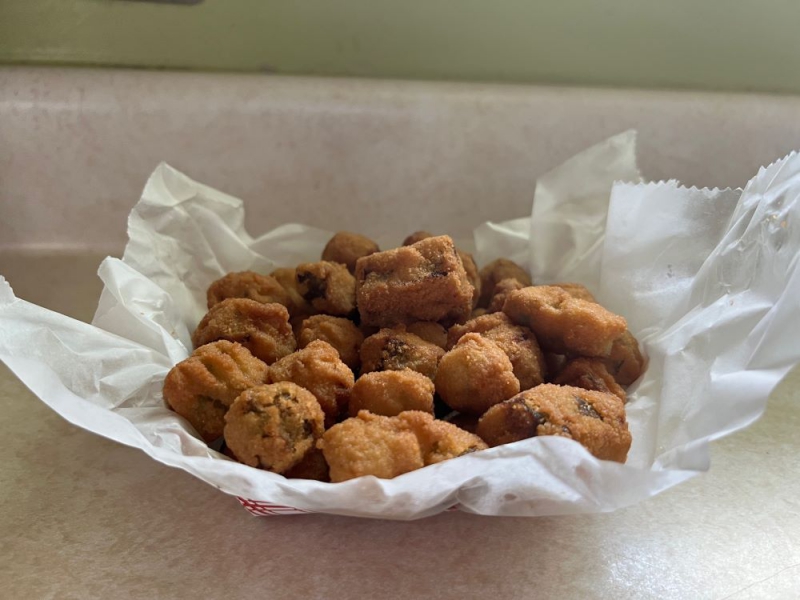 A red and white cardboard container is line with wax paper and filled with small bites of breaded and fried okra. Photo by Julie McClure.