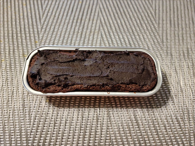 An oblong tin with a gluten free iced fudge brownie in a metal tin. Photo by Matthew Macomber.