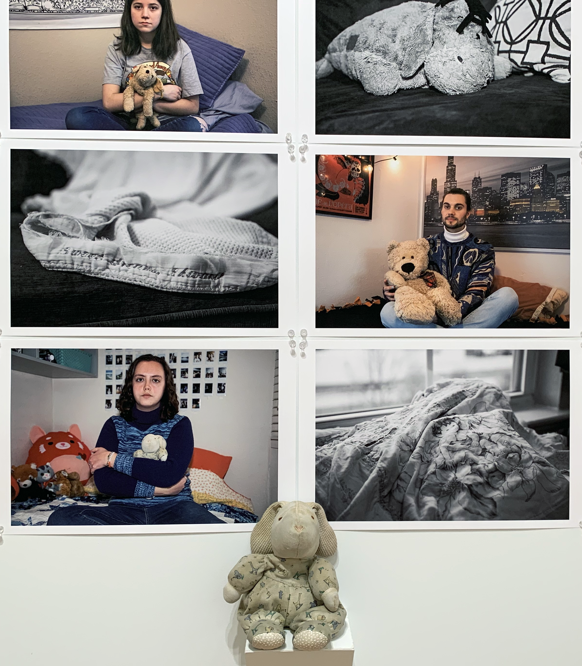 Photographs of people with baby blankets and teddy bears behind a teddy bear on a shelf.