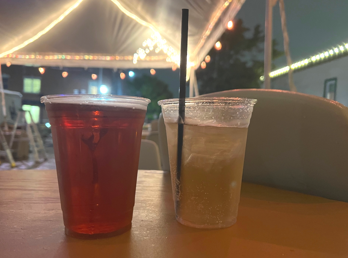 On a wooden table under a tent at the Rose Bowl Tavern, two plastic cups hold alcoholic drinks. Photo by Alyssa Buckley.