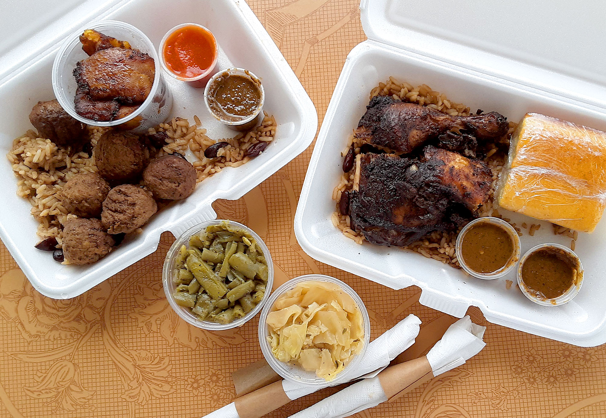 On a brown table, there are two takeout containers and two cups of sides. Photo by Paul Young.