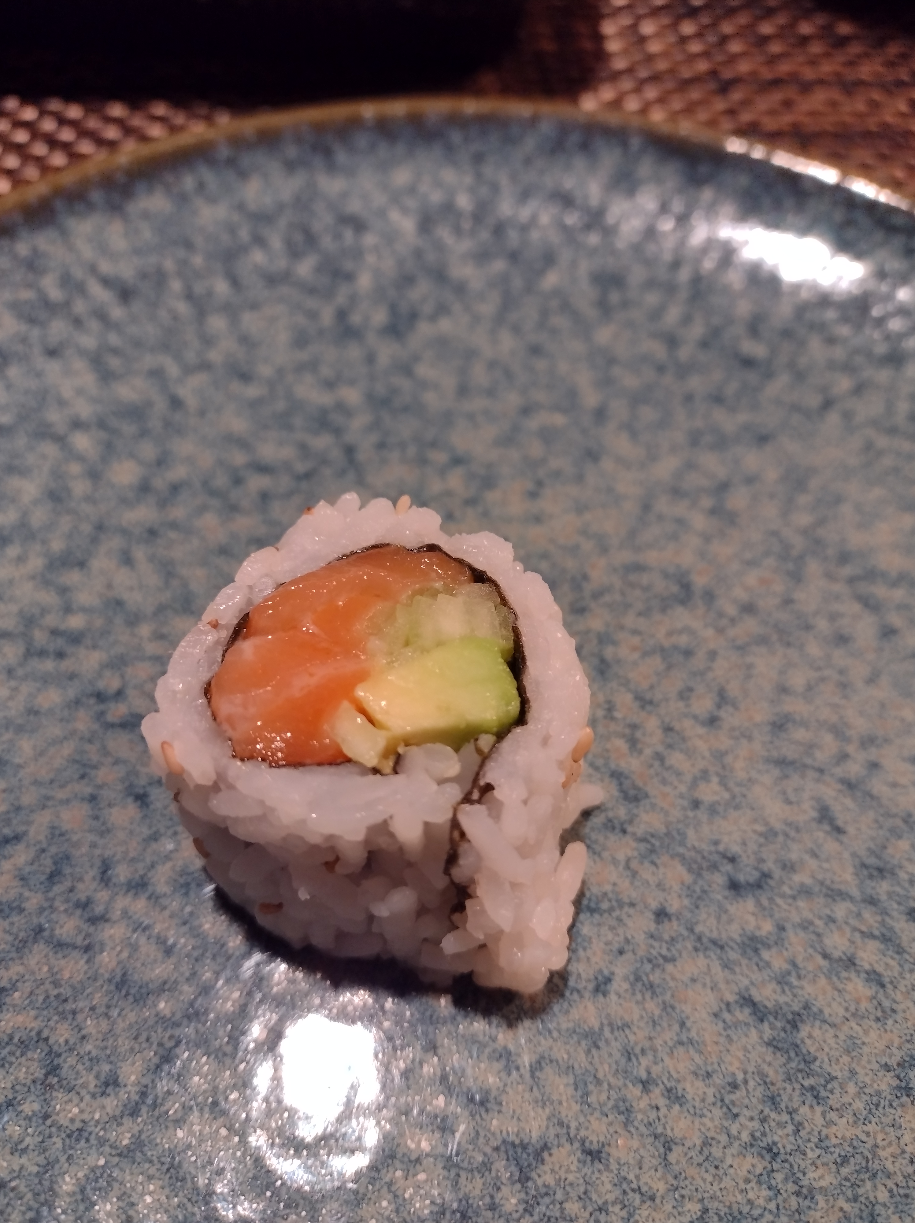 One piece of Alaska roll sits on a blue plate. Photo by Melkior Ornik.