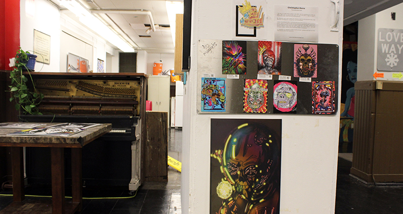 On the left is a piano and at center is a series of magnets and prints on a square pillar.