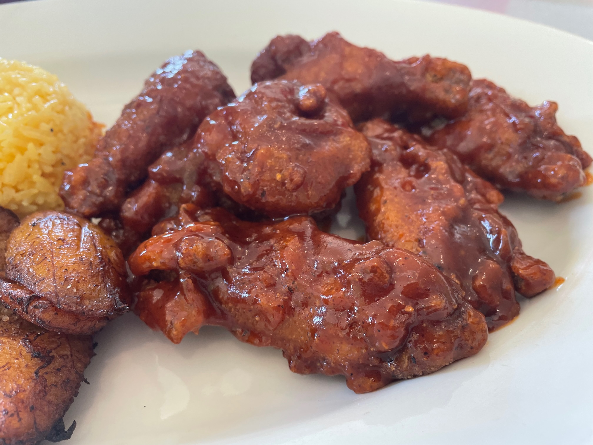 On a white plate, there are sauce up Zambian fried chicken wings from Stango Cuisine in Urbana, Illinois. Photo by Alyssa Buckley.