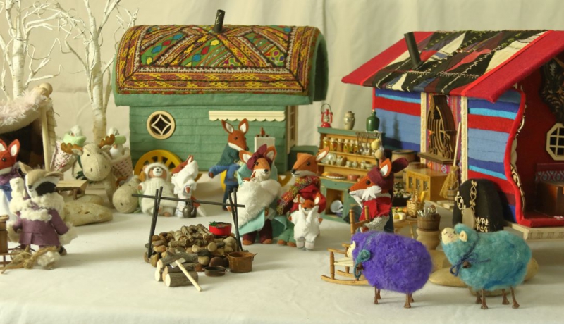 An image of a section of Barbara Schoenoffâ€™s multi-part assemblage entitled, Rendezvous. The assemblage, consisting of over 300 individual items, depicts a meeting between various nomadic people with wagons, tents, and other items set up for camp. The â€œpeopleâ€ in the camp are animals of one kind or another: foxes, lions, badgers, and others. A firepit (for cooking) is visible in the foreground.
