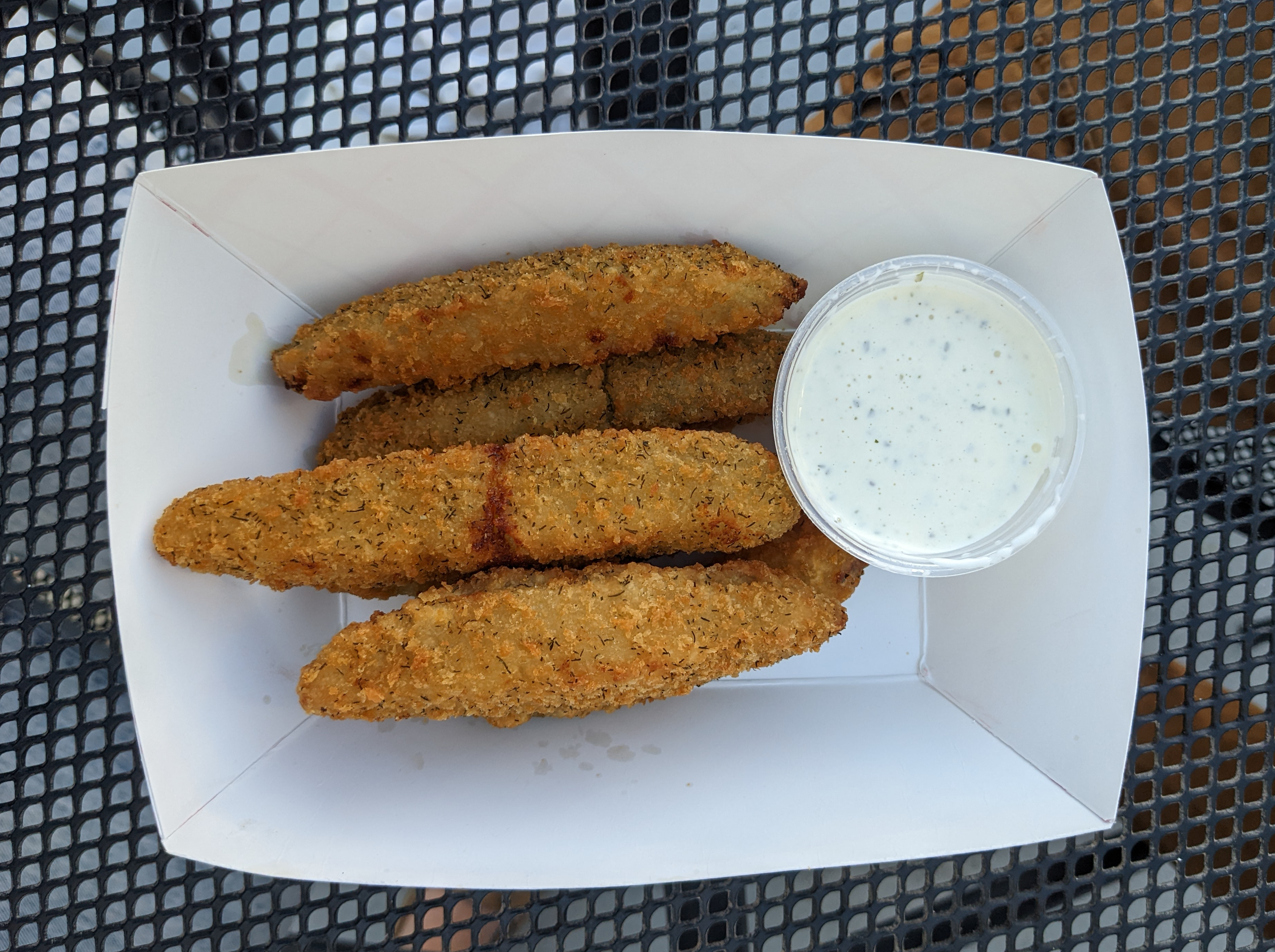 On a black bistro table outside at Bunny's Tavern in Urbana, there is a paper basket of five fried pickle spears. Photo by Tayler Neumann.