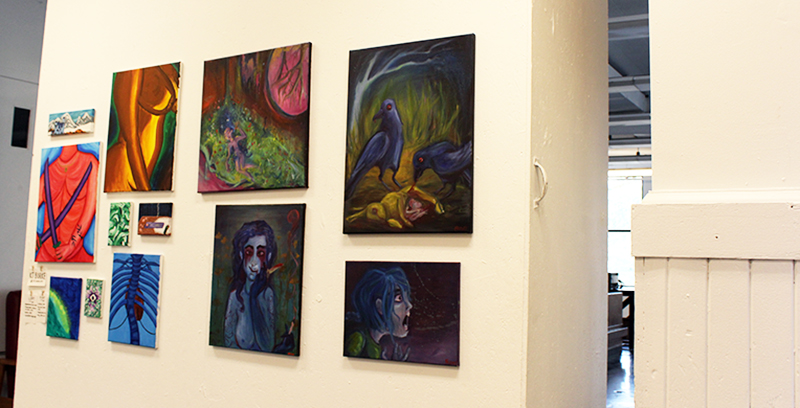A series of dark toned paintings on a central wall.