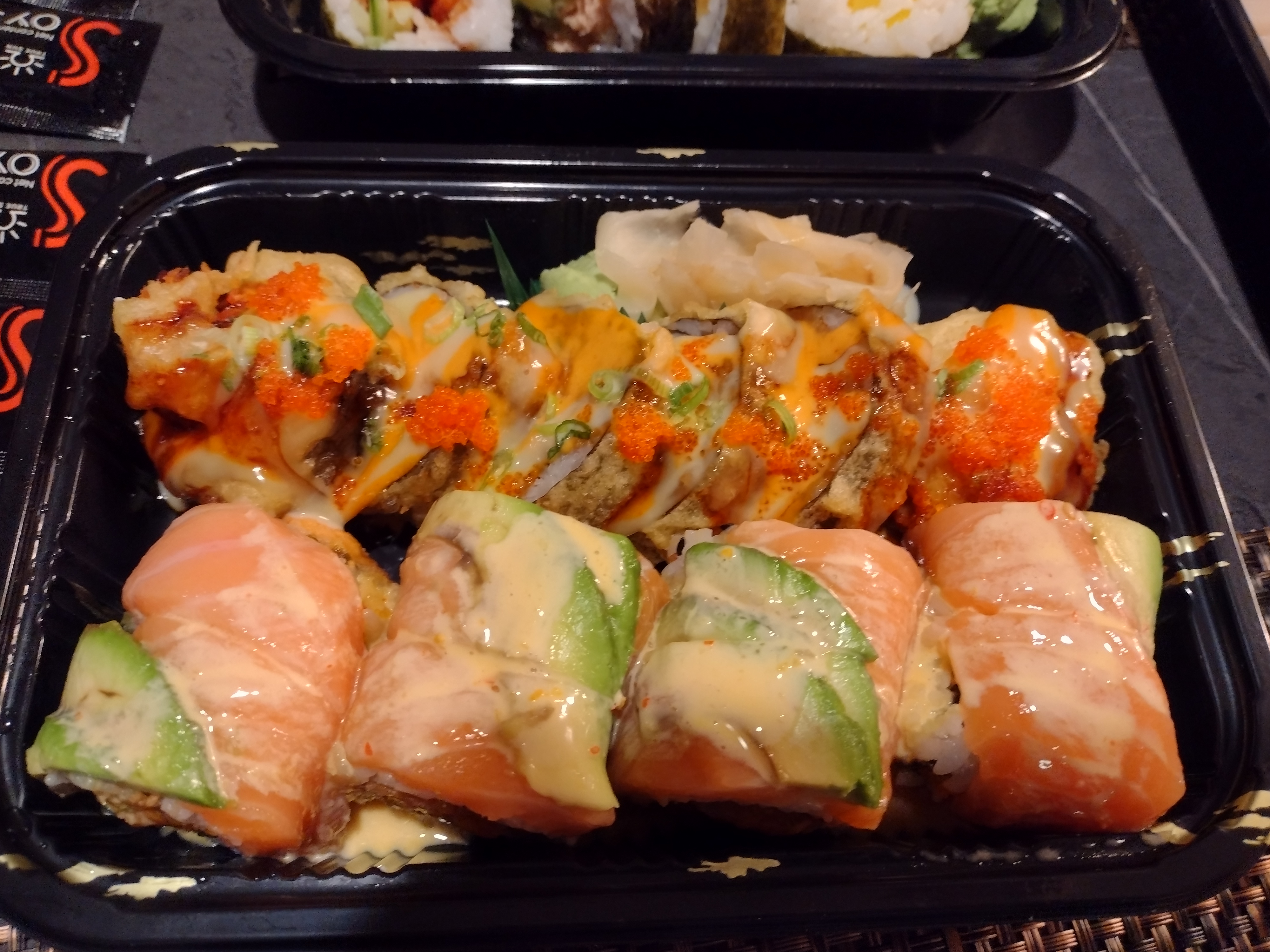 In a takeout container, there are two saucy sushi rolls from Sushi Man. Photo by Melkior Ornik.