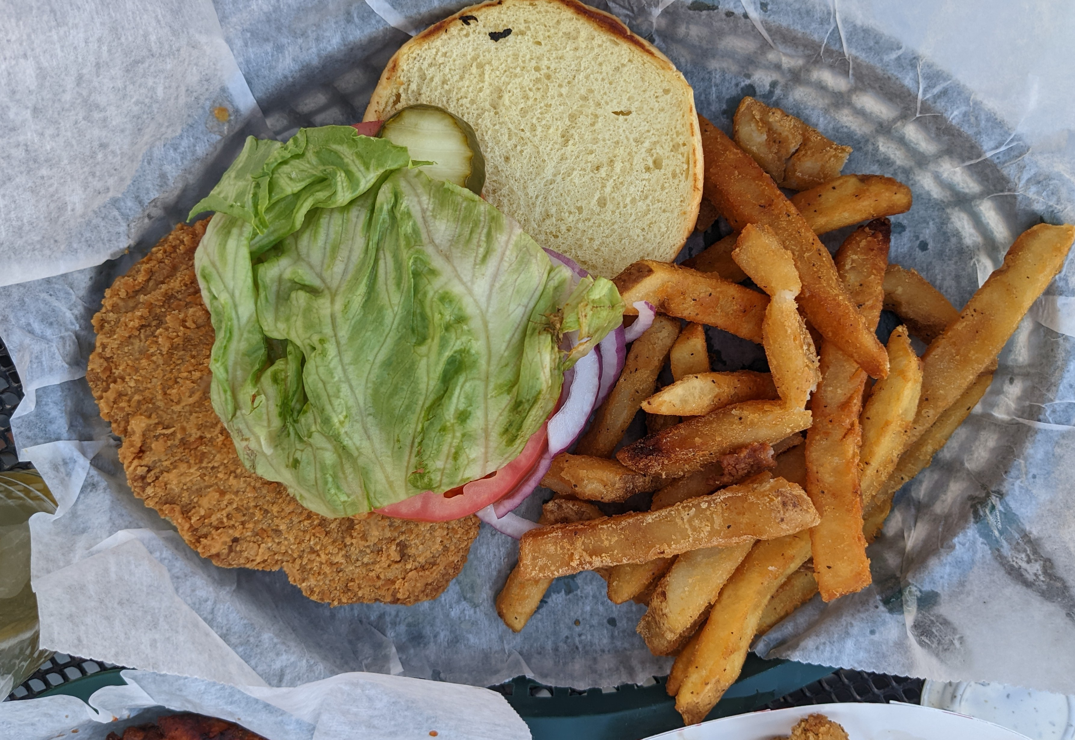 An overhead photo shows Bunny's breaded pork tenderloin sandwich with lettuce and fries. Photo by Tayler Neumann.