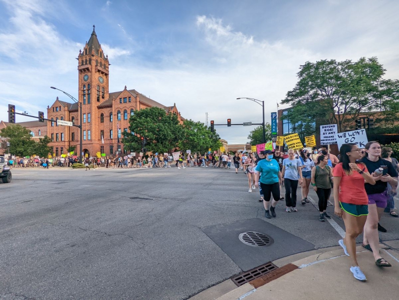 The march begins at the corner of Main and Broadway under a cloudy blue sky where masked and unmasked protesters start heading west on the sidewalk carrying hand-made and pre-printed signs. Photo by Brandi MV McCoy.