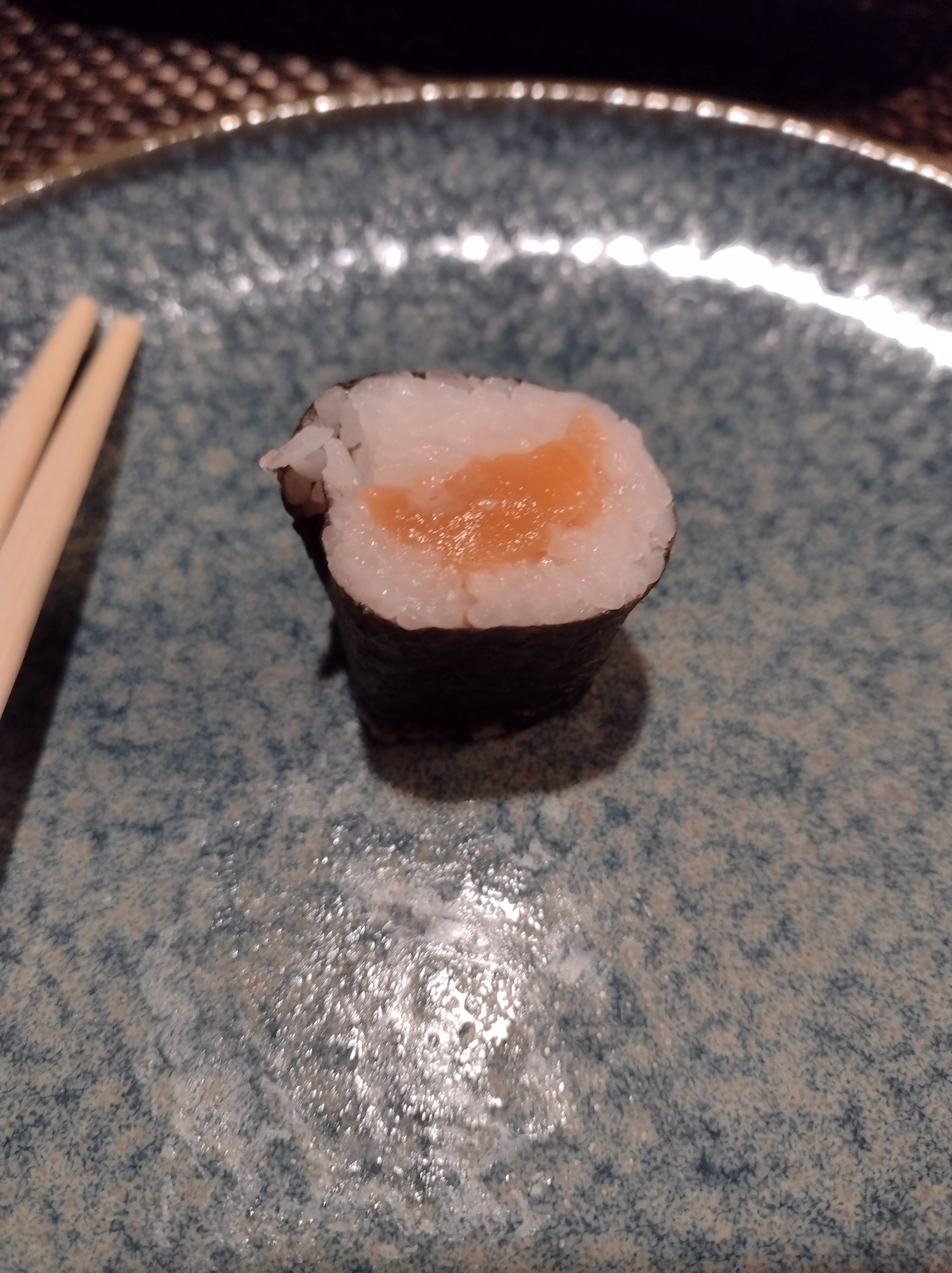 One piece of salmon sushi sits on a blue plate. Photo by Melkior Ornik.