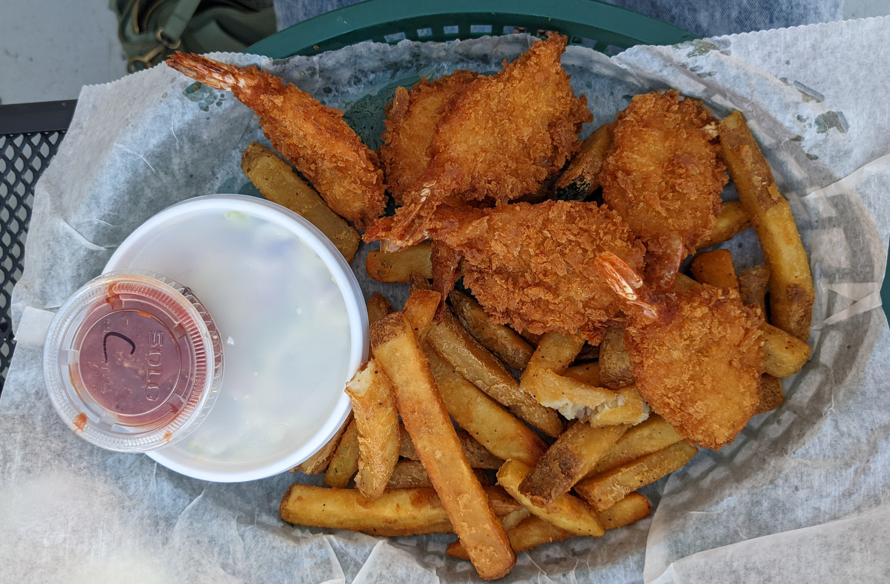 An overhead photo shows the fried shrimp basket from Bunny's with six jumbo fried shrimp, fries, coleslaw in a white styrofoam cup, and a little cup of sauce. Photo by Tayler Neumann.