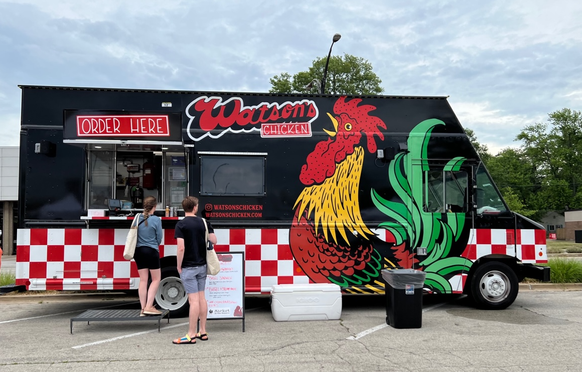 In the parking lot of Urbana's Market at the Square, the Watson's food truck is parked with two white patrons waiting to order. Photo by Alyssa Buckley.