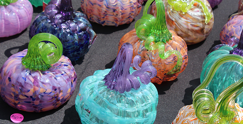 A display of small handblown glass pumpkins in a variety of colors and color combinations.