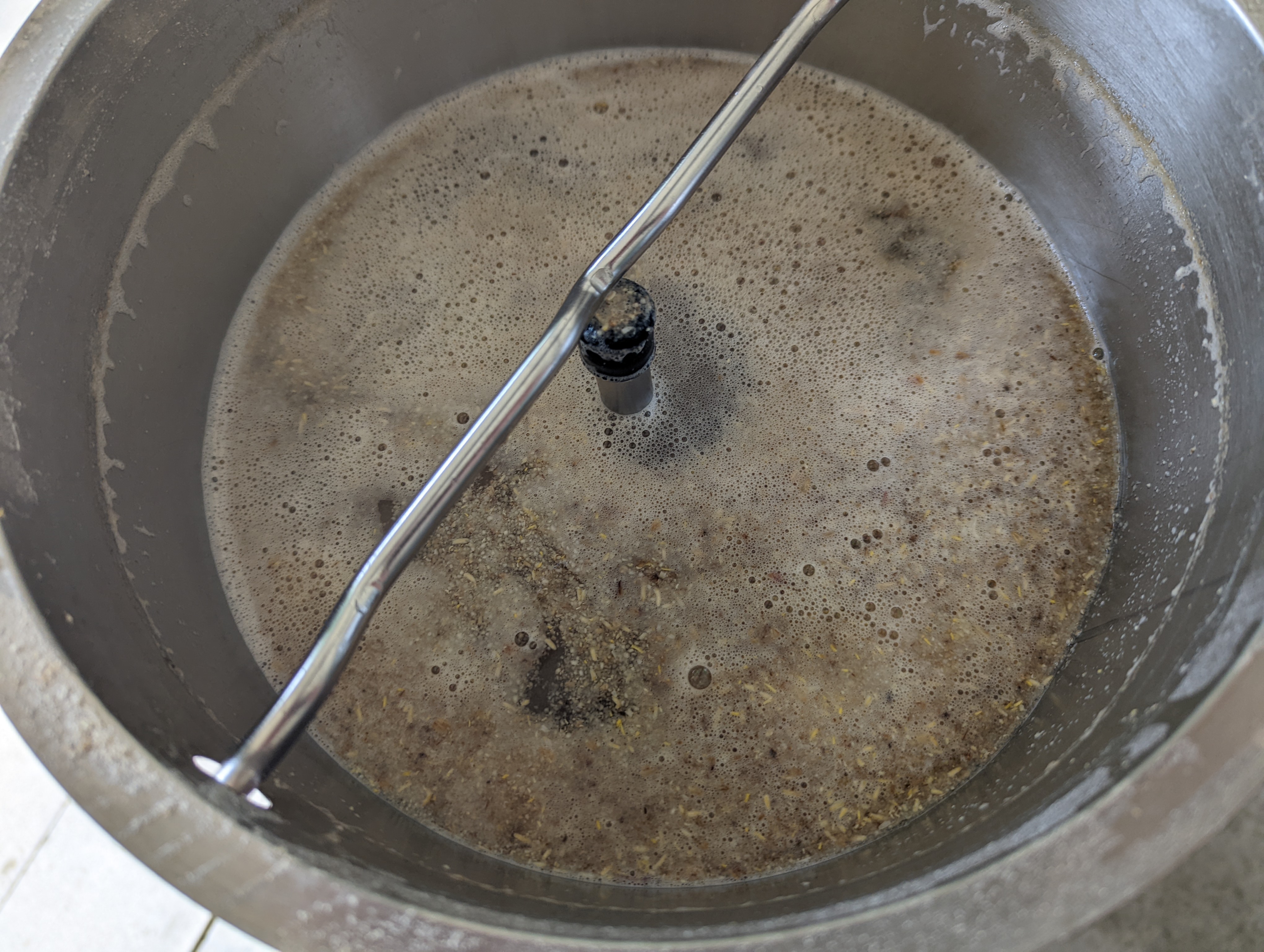 An overhead photo shows a metal bowl with fermenting beer. Photo from BUZZ Homebrew Club.