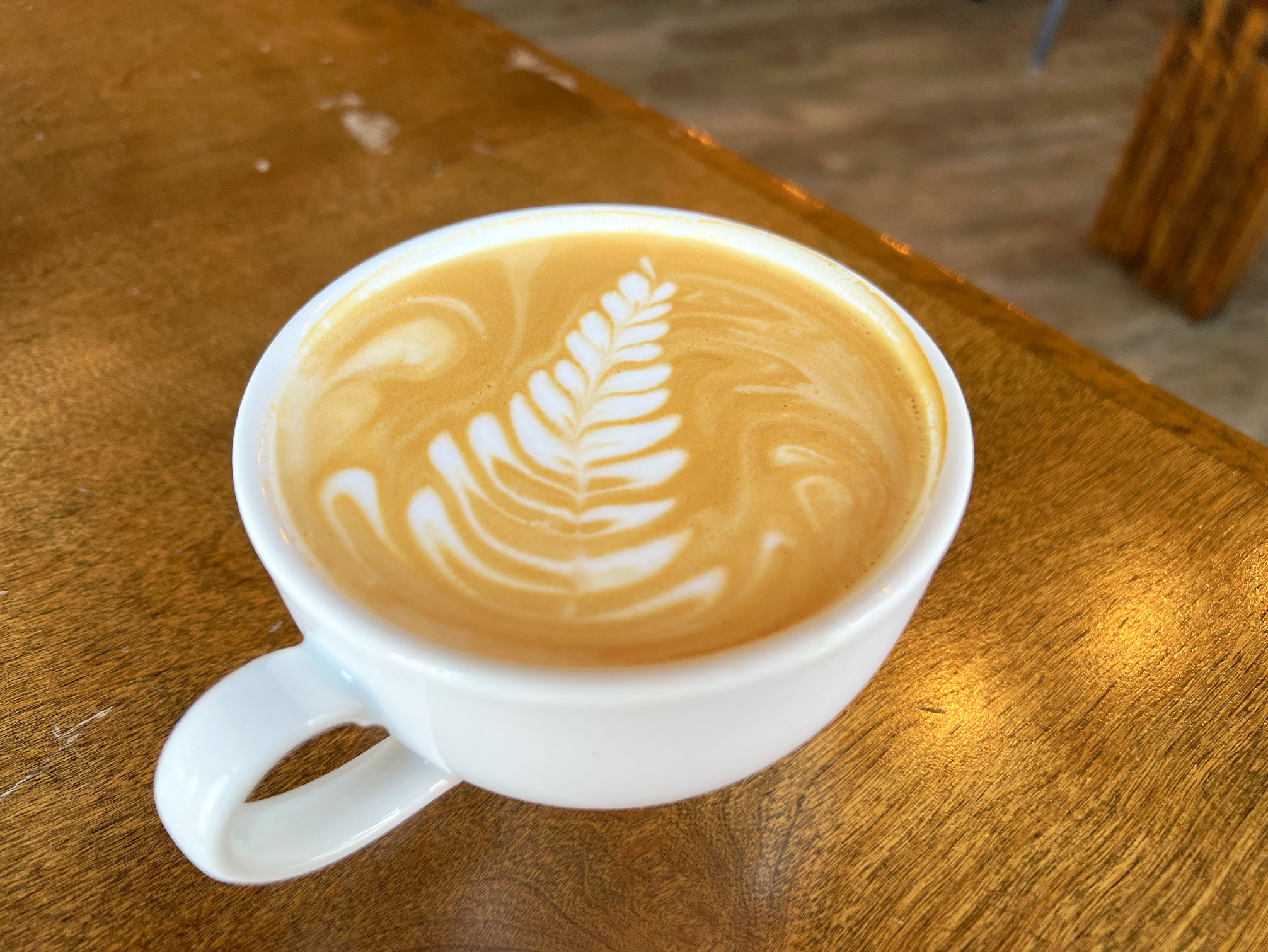 On a wooden table at Flying Machine Avionics, there is a harvest moon latte with a pretty foam design. Photo by Alyssa Buckley.