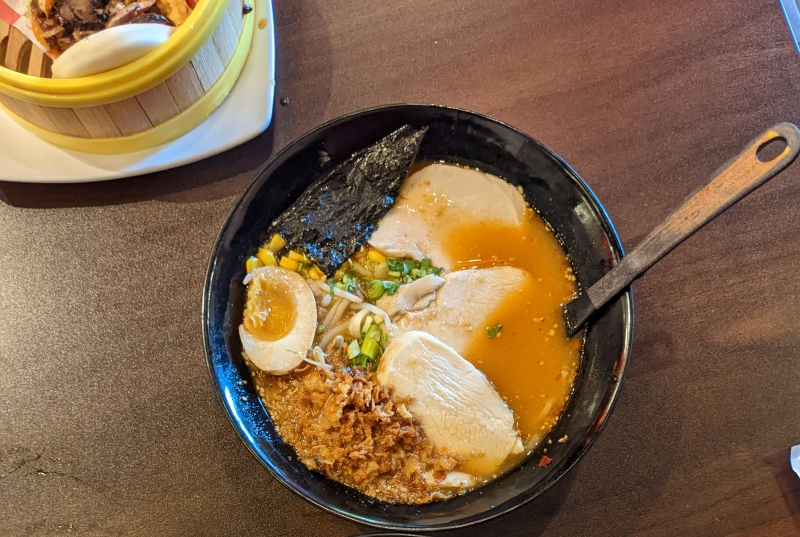 Spicy chicken ramen. Thick slices in a bowl with corn, seaweed, a seasoned egg and brown broth. Photo by Caitlin Aylmer.