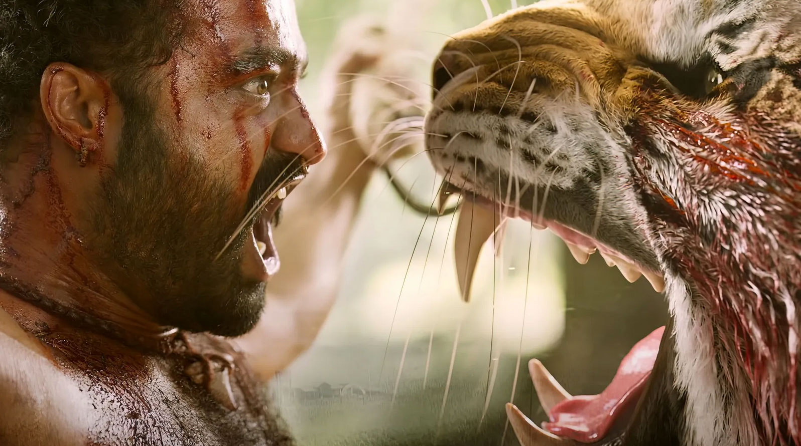 A film still from the movie RRR depicting a man facing a very large tiger in close-up; both creatures are roaring at each other. Photo by Netflix.
