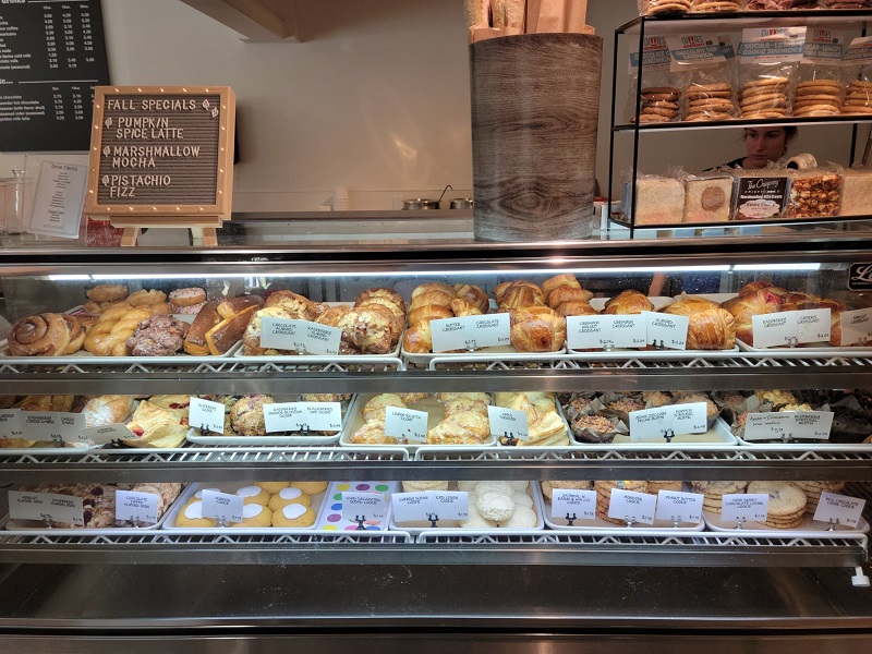 CafÃ© scones, cookies, donuts, and other pastries on a display shelf with the fall drink specials list shown (marshmallow mocha, pumpkin spice lattes and pistachio fizz). Photo by Matthew Macomber.