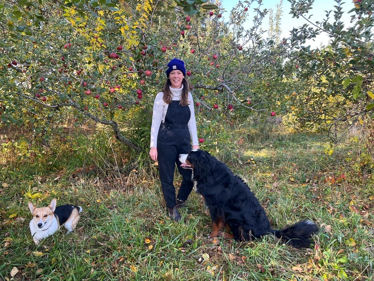 Molly Oberg poses with her farm dogs Sheeba and Violet on the Meyer Produce farm in the apple orchard. Photo by Alyssa Buckley.