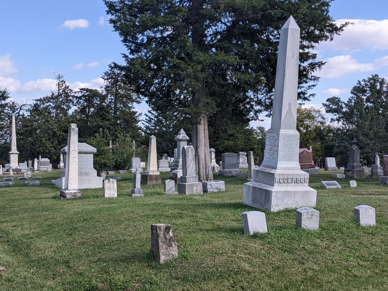 A closer view of a collection of headstones, many with a tall pointed monument. Photo by Tom Ackerman.