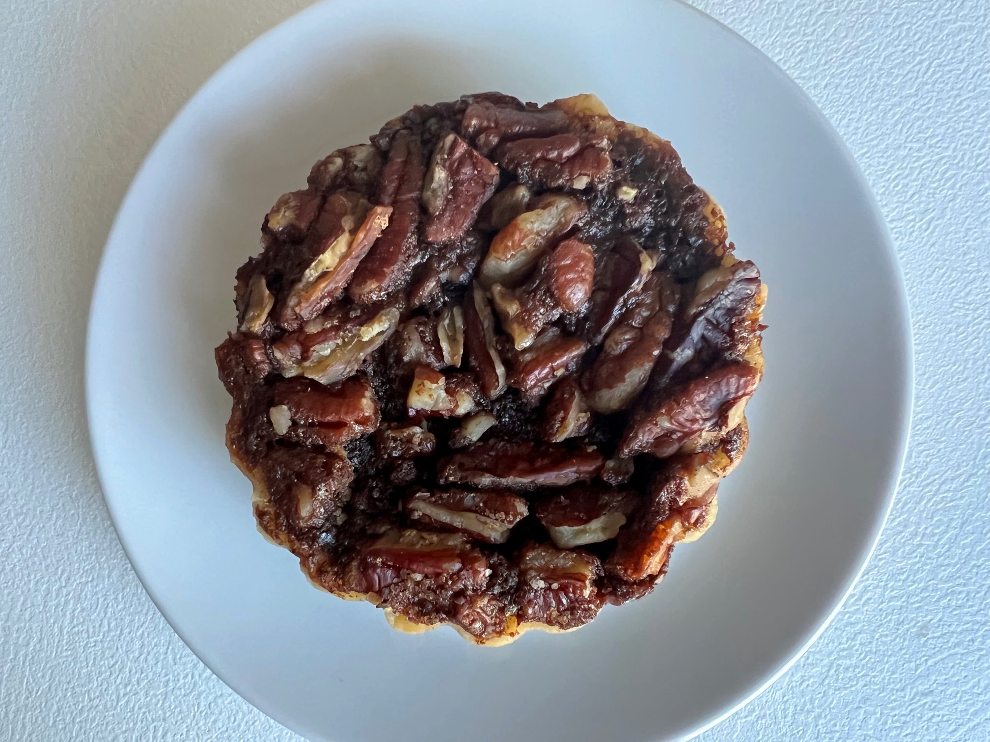On a white plate, there is a mini chocolate pecan pie. Photo by Alyssa Buckley.