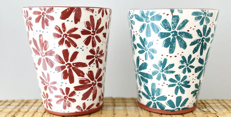 Two ceramic v-shaped cups with dainty red and teal flowers. 
